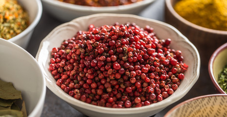 Pink peppercorn and variety spices and herbs in bowls