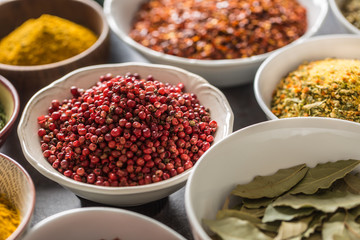 Pink peppercorn and variety spices and herbs in bowls