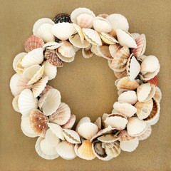 Scallop seashell wreath on beach sand beach background. Top view.