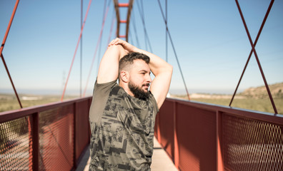 Bearded man stretching and training on a bridge