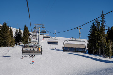 Chairlift with people at ski resort, blue sky in winter