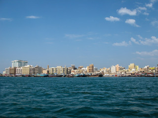 modern buildings on coast of bay deira creek and old-fashion traditional boats in Dubai, UAE