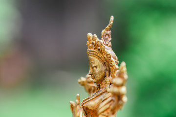 Figure of a female Buddhist deity (Green Tara) sitting on a lawn 
