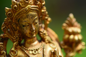 Figure of a female Buddhist deity (Green Tara) sitting on a lawn 