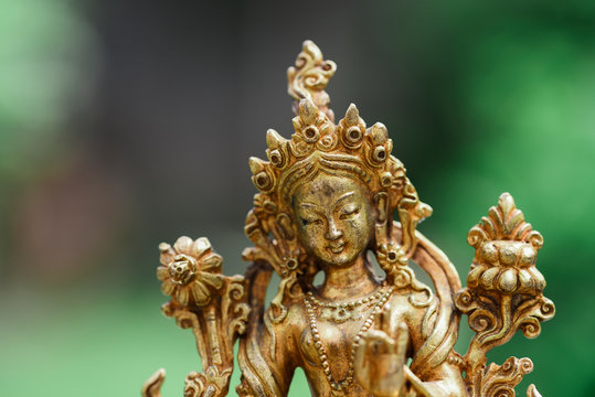 Figure of a female Buddhist deity (Green Tara) sitting on a lawn 