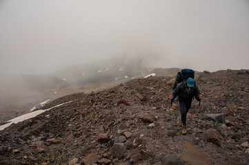 Experienced traveller climbs up the foggy mountain
