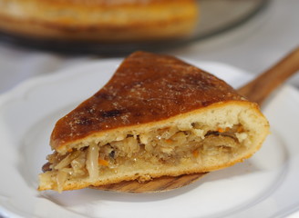 Round homemade pie with cabbage and river fish pike. Wooden rustic white table. Homemade food.