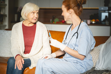 Obraz premium Serious blonde mature woman sitting near doctor