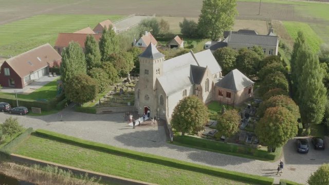 Aerial of people arriving to wedding in catolic church in small green  town