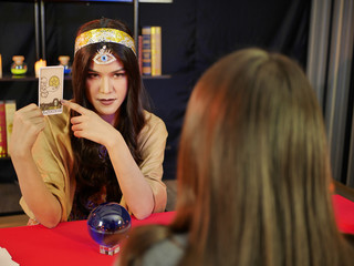 the asian lady fortune teller using blue clear crystle and tarot cards by divine occult mystic magic power 