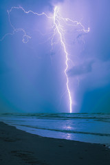 Long bright lightning strike over sea
