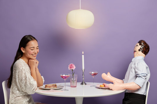Relationship simulations concept. Romantic woman admires her unreal lover, starts serious relations, dreams about dating, being invited for date, believes in love story, has dinner with male doll