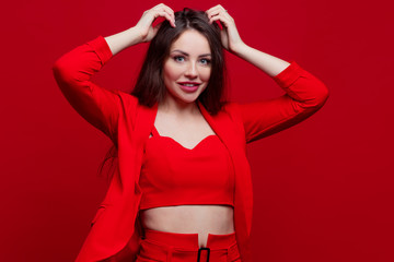 Stylish young woman in a red suit on a red background.