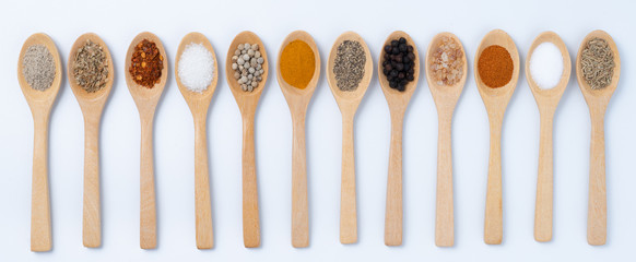 Various spices in wooden spoons, isolated background
