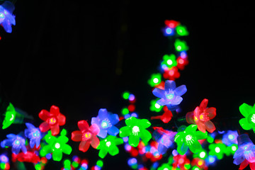 Colorful light bulbs in the form of flowers. A shining tree of multicolored flowers. A bright...