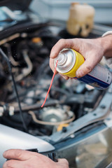 Hands cleaning a detail of a car's engine