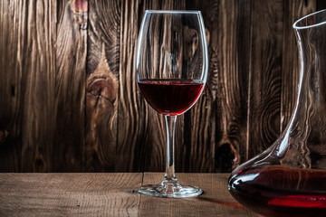 glass and decanter with red vine on vintage wooden background very close up