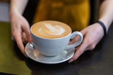 coffee in the hands of a girl on a brown background