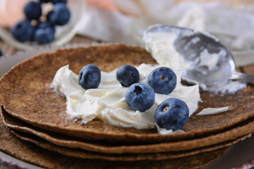 Thin rye tortilla stuffed with soft curd cheese like riccott with blueberries, close up