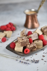 Oriental sweets, halva slices on a metal dish, decorated with raspberries, with Turkish coffee. Background, vertical.
