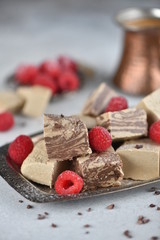 Oriental sweets, halva slices on a metal dish, decorated with raspberries, with Turkish coffee. Background, macro, vertical.