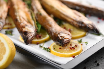 Whole fish, fried or smoked, on a baking sheet with lemon and herbs.