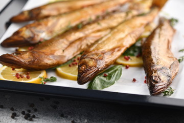 Whole fish, fried or smoked, on a baking sheet with lemon and herbs.