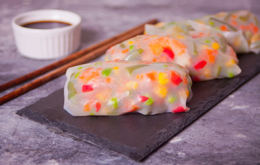Spring rolls with vegetables and rice paper on the black plate
