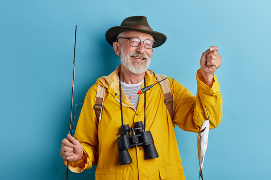 smiling cheerful old fishman boasting about his catch, close up photo. isolated blue background,