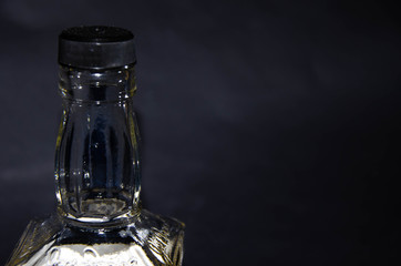Bottle of whiskey half full on a black background. Bottle in a man's hand. Single malt whiskey....