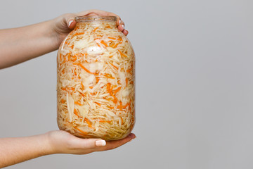 Isolated sauerkraut. jar of sauerkraut in women's hands