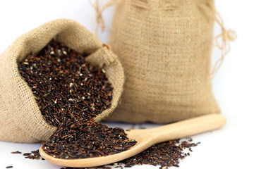 Riceberry In a wooden spoon and in a sackcloth isolated on white background