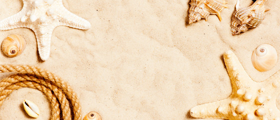 Fototapeta na wymiar Rope and shells on the sand, travel summer banner