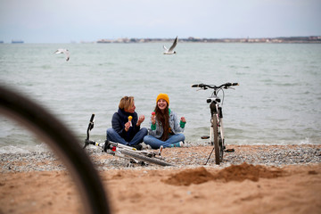 girl friends eat ice cream near the sea in winter