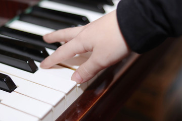Obraz premium The piano close up. Black and white keys.Hands of a child playing the piano