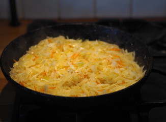 Home cooking. Fried cabbage in a black pan over a fire. Preparing the filling for the pie with cabbage.