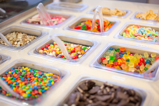 A view of several containers full of popular ice cream toppings on display at a local ice cream shop.