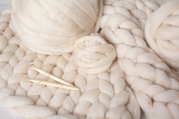 Fototapeta na wymiar a ball of thick yarn and wooden needles lie on a blanket of Merino wool