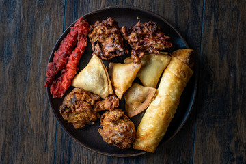 Indian Food Plate with Chicken Pakora, Aloo Tikki, Samosas Samsa and Spring Rolls.