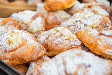 A closeup view of several almond croissants on display at a local bakery.