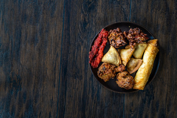 Indian Food Plate with Chicken Pakora, Aloo Tikki, Samosas Samsa and Spring Rolls.