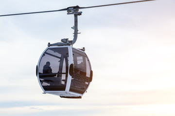 Cabin of a gondola cableway suspended on a rope where sits people with skis and snowboards high in the Altai mountains with snow and blue sky on winter sunset. Ski resorts and snowboarding. © Aleksandr Kondratov