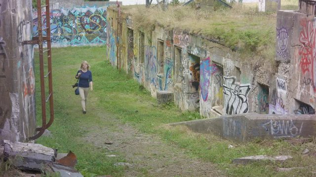 Young woman walks between the ruins of an old military base