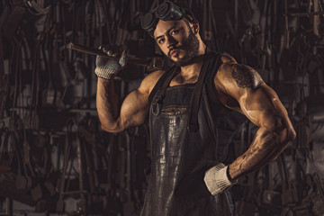 Fototapeta na wymiar confident forger in leather uniform isolated in workshop. special equipment. strength and power concept. muscular body