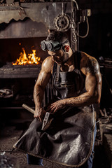 Obraz premium portrait of strong muscular handsome forger in leather uniform isolated in workshop, furnace fire in the background