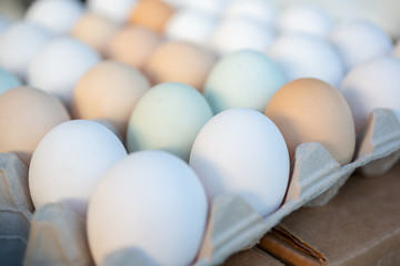 A view of several different colored chicken eggs on display at a local farmers market.