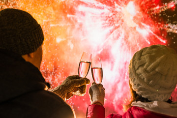 Merry man and woman in the winter clothes toasting with glasses champagne celebrate holiday...
