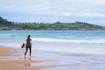 Woman running out to sea on a surfboard wearing a wetsuit, copy space