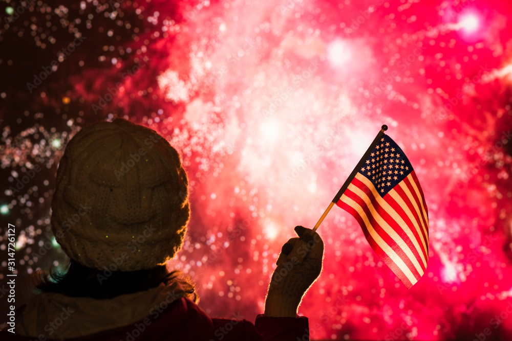 Wall mural fireworks at night. woman in winter clothes with american flag.