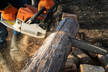 Man is sawing a log with a chainsaw